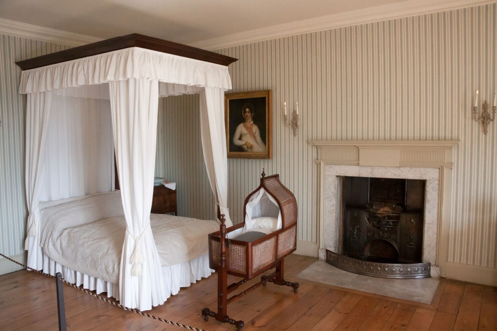 Kristin Holt | #WhyIWriteHistoricals. Photograph: 19th century bedchamber (showing canopied bed and baby basinette beside fireplace. Room appears to be in a museum home.