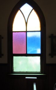 Colored glass windows along the sides of the historic Our Lady of Tears Catholic Church in Silver City, Idaho. Because of the nature of the building and climate (shifting and settling), the windows are frequently broken. Replacements are true to history.