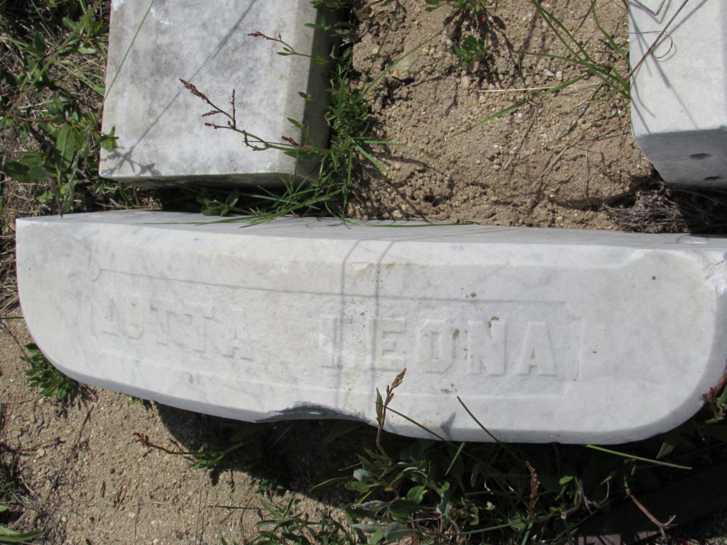 Kristin Holt | Silver City, Idaho's Ghost Town Cemetery. Footstone at the bottom of 1 year-old Lotta Leora Williams's grave. The side blocks of granite outline the child-size burial plot. Image: Kristin Holt, June 2016.