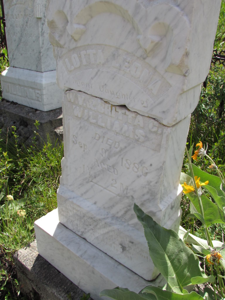 Kristin Holt | Silver City, Idaho's Ghost Town Cemetery. Lotta Leona, Infant daughter of W.V. & Britta C. Williams, Died Sep. 9, 1886, Aged 1 Y, 2 M. In the background, far left, Lotta's father's stone is visible. It reads: William V. Williams, born Aug 11, 1846. Died April 25, 189(5?). Image: Kristin Holt, June 2016.