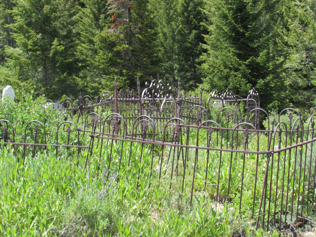 Kristin Holt | Silver city, Idaho's Ghost Town Cemetery. One common feature of Victorian-era cemeteries are fences around individual or family plots within the larger cemetery. Such Mourning Fences were available for purchase from catalogues such as Montgomery Ward & Co. This image shows several separate fences encompassing small family plots of two to four graves each. Image: Kristin Holt, June 2016.
