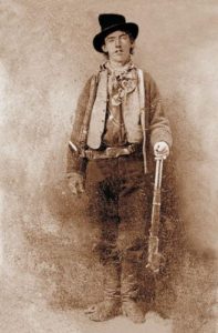 Portrait of American gunman Billy the Kid (1859–1881). Image mirrored on vertical axis to correct widely-seen flopped tintype. Cartridge loading gate on Winchester Model 1873 lever action rifle is on the right side of the receiver. Image: Public Domain, courtesy of Wikipedia