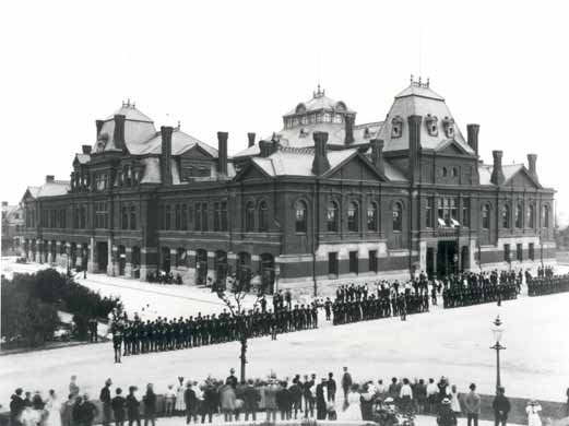 Kristin Holt | U.S. Marshals: In the Beginning. Vintage Photograph: Pullman strikers outside Arcade Building in Pullman, Chicago. The Illinois National Guard can be seen guarding the building during the Pullman Railroad Strike in 1894. Image: Public Domain, courtesy of Wikipedia.