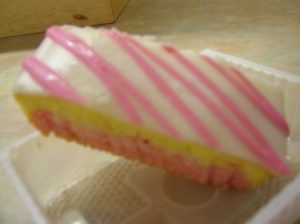 Kristin Holt | Victorian Cooking: Angel's Food Isn't Always Angel's Food. Photograph of British Angel Cake, with pink and white icing upon multi-color cake.