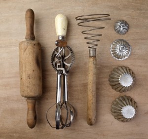 Kristin Holt | NEW RELEASE: Opening Scene. Photograph of antique rolling pin, egg beater, potato masher, cookie cutters and/or gem pans. Purchased from Shutterstock.