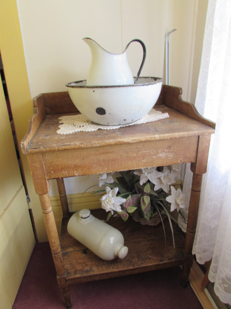 Kristin Holt | Historic Idaho Hotel in Silver City. "Toilet", a.k.a. wash stand with pitcher and bowl. On the bottom shelf, see the antique bed warmer. Historic Idaho Hotel, Silver City, Idaho.