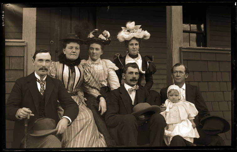 Kristin Holt | Historic Silver City, Idaho. Vintage photograph of a group on a residential porch in Silver City, Idaho. Individuals are mostly unidentified. Furthest left is Henry Swanholm, next to him is Permeal French the first woman to serve as State Super of Public Instruction, 1898-1903. Child is Lucielle Lippincott. Image: Public Domain. Image courtesy of Idaho State Archives, Idaho state Historical Society. Identifier: P1960-139-9.