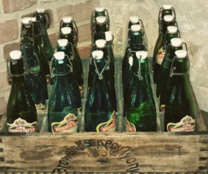 Kristin Holt | Victorian Americans Celebrate Oktoberfest. Green glass bottles with a mechanical stopper, in a vintage wooden carrying box.