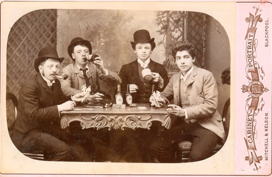 Antique cabinet card photograph of young men smoking, drinking, and gaming.