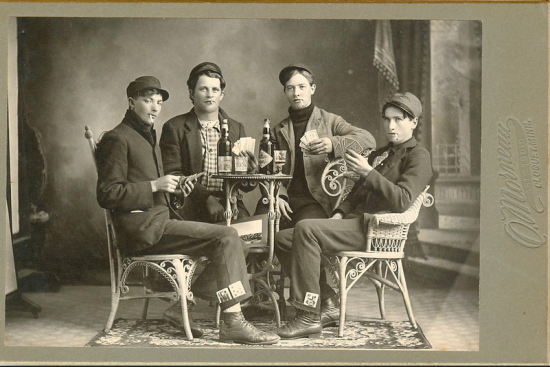 Antique cabinet card photograph of young men smoking, drinking, and gaming.